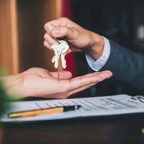 estate agent giving house keys to woman and sign agreement in office